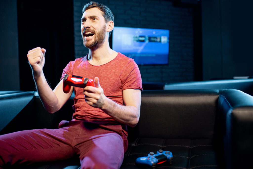 Happy man playing video games with gaming console in the club